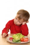 three years old boys and plate of fresh vegetables isolated on white